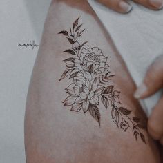 a woman's thigh with flowers and leaves on it