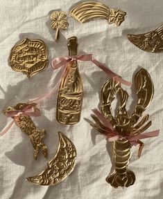 some gold ornaments are laying on a white sheet and tied with pink ribbon around them