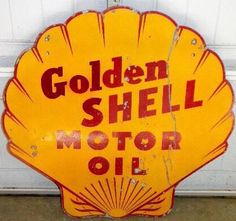 an old yellow shell motor oil sign hanging on the side of a garage door,