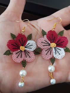 a pair of pink and white flowers with pearls on the end of each dangle