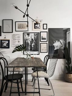 a dining room table with chairs and pictures on the wall above it in black and white