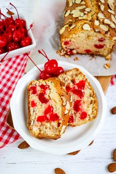 two pieces of bread on a plate with cherries and almonds next to it