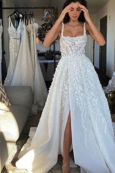 a woman standing in front of a mirror wearing a white wedding dress with high slit