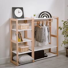 a white shelf with clothes hanging on it and a clock in the corner next to it