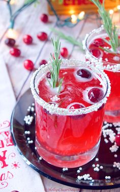 two glasses filled with red liquid and garnished with rosemary