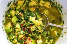 a white bowl filled with green soup and tofu