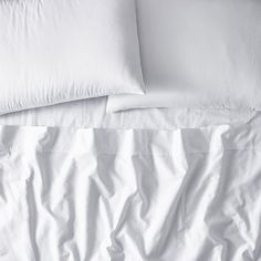 an unmade bed with white sheets and pillows