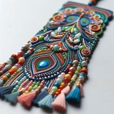 a colorful beaded bracelet with tassels and beads on the end is laying on a white surface