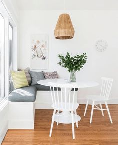 a white table and chairs in a small room with wood flooring next to a window