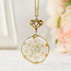 "Handmade real birth flower necklace featuring a dried pressed Narcissus flower pendant. The birth flower is adorned with Queen Anne's lace and gold flakes. The beautiful dried flower pendant is embedded in a UV resin 32mm (1.26 inch) round irregular setting and is available in a gold or silver finish. The high quality stainless steel beaded chain is enhanced by a Victorian style floral bail. You can choose your chain length between 18\", 20\", 24\", 30\" inches. Your jewelry will arrive in a lo White Flower Pendant Necklace With Birth Flower, White Flower Pendant Necklace With Pressed Flowers, Nature-inspired White Necklace With Pressed Flowers, White Nature-inspired Necklace With Pressed Flowers, White Necklaces With Pressed Flowers For Mother's Day, White Pressed Flowers Necklace For Mother's Day, White Birth Flower Necklace, Flower Pendant Necklace With Pressed Flowers, White Flower Necklace With Pressed Flowers