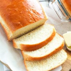 sliced loaf of bread sitting on top of a cutting board next to butter and knife