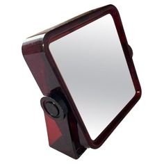 a mirror with a red frame and black handle on the front is shown against a white background