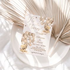 a teddy bear themed wedding card on a plate next to palm fronds and a fan