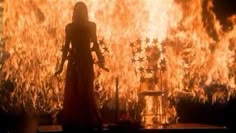 a woman standing in front of a huge fire with flames coming out of her back