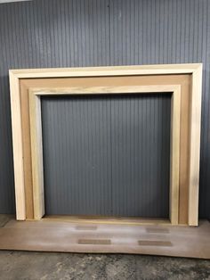 a wooden frame sitting on top of a floor in front of a gray wall with vertical blinds