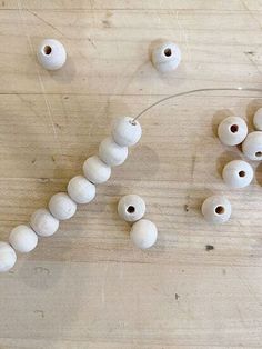 several white beads on a wooden surface with string attached to the bead and thread