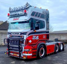 a red and silver semi truck parked in a parking lot