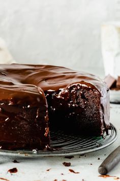 a chocolate cake on a plate with one slice cut out and ready to be eaten