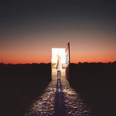 a person standing in an open doorway at night with the sun setting behind them and stars above