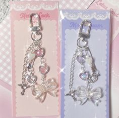 two key chains with charms attached to them on a pink and white carded background