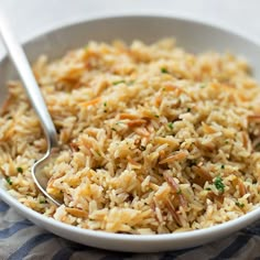 a white bowl filled with rice on top of a blue and white table cloth