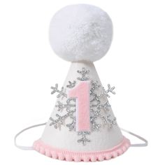 a white and pink birthday hat with snowflakes on the top, one year old