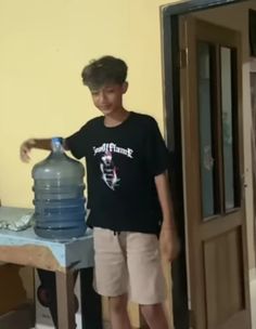 a young boy standing next to a large water bottle