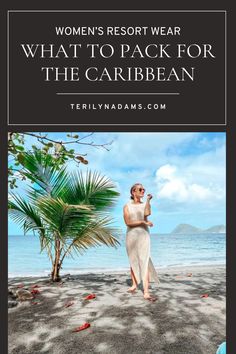 a woman in white dress standing on the beach with palm trees and water behind her