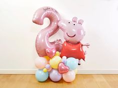 the balloon is shaped like a number, with balloons surrounding it and a peppa pig sitting on top