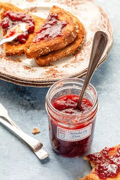 two slices of toast with jam on them and a spoon next to it, sitting on a plate