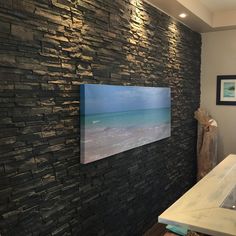 a stone wall in a bathroom with a painting on the wall and a sink below it