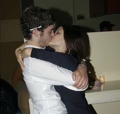 a man and woman kissing each other in front of a sink