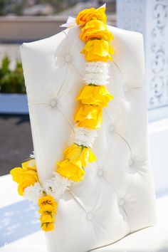 yellow and white flowers are arranged on the back of an upholstered chair for a wedding ceremony