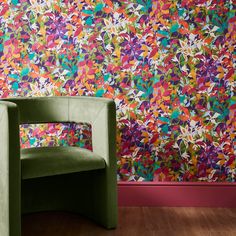 a green chair sitting in front of a wall with colorful paint on it's walls