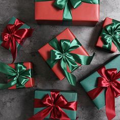 four wrapped presents with red and green bows on them, all tied up in different colors