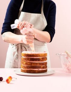 a woman in an apron is decorating a cake