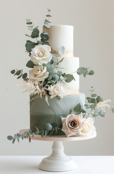 a three tiered cake with white flowers and greenery