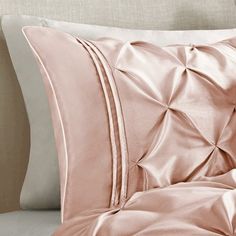 a close up of a pillow on a bed with sheets and pillows in the background