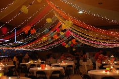 a room filled with lots of tables covered in white tablecloths and colorful lights