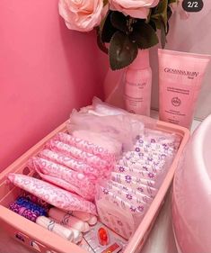 a pink box filled with personal care items next to a flower vase and toiletries