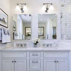 a white bathroom with double sinks and mirrors