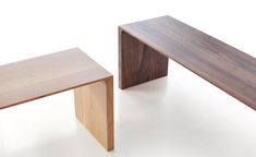 two wooden benches sitting next to each other on a white surface with no one around them