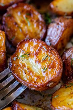 a fork with some food on it next to potatoes and other foods that have been cooked