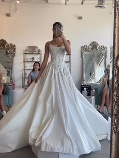 a woman in a wedding dress is taking a selfie with her cell phone as she stands in front of a mirror