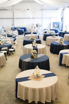 tables with blue and white linens are set up in a large tent for an event