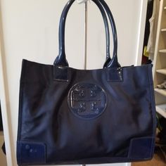 Durable Nylon With Patent Leather Details In Navy Blue. Features A Magnetic Snap Closure, 1 Interior Zipper Pocket, 2 Slit Pockets. Normal Wear And Tear. In Great Condition - Only Used A Few Times. Height 10.6", Length: 13.6", Depth: 4.4" Tory Burch Ella, Tory Burch Bags, Tory Burch Bag, Mini Tote, Womens Tote Bags, Snap Closure, Ted Baker Icon Bag, Patent Leather, Zipper Pocket