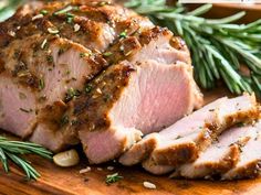 sliced pork on a cutting board with rosemary sprigs and seasoning around it