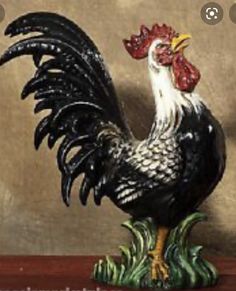 a black and white rooster figurine sitting on top of a wooden table next to a brown wall