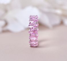 a pink ring sitting on top of a table next to some white flowers and petals