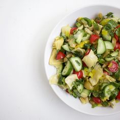 a white bowl filled with cucumber, tomato and lettuce salad on top of a table